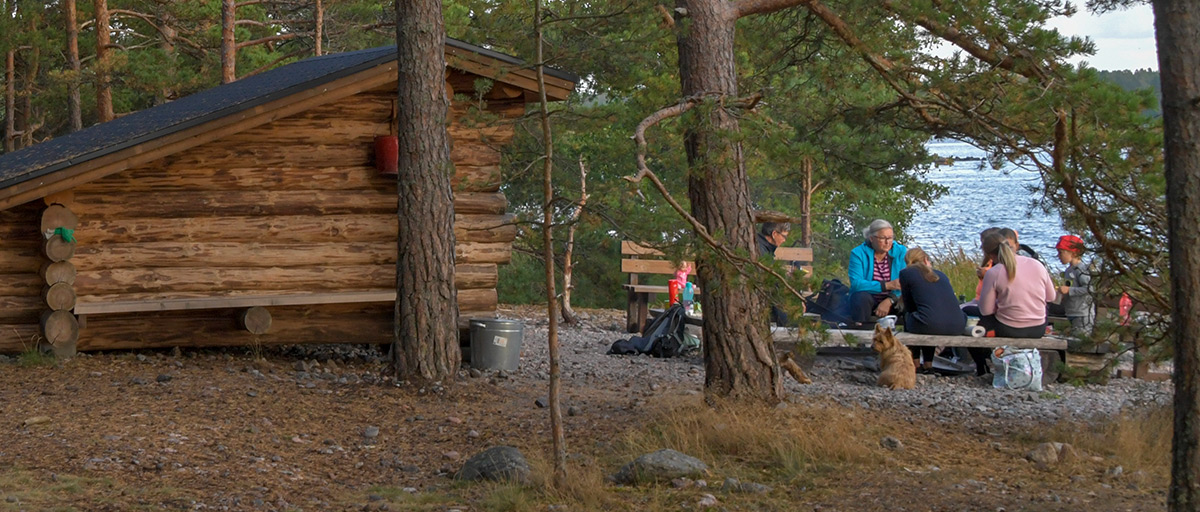 Ihmisiä kokoontunut laavulle ja nuotiopaikalle.