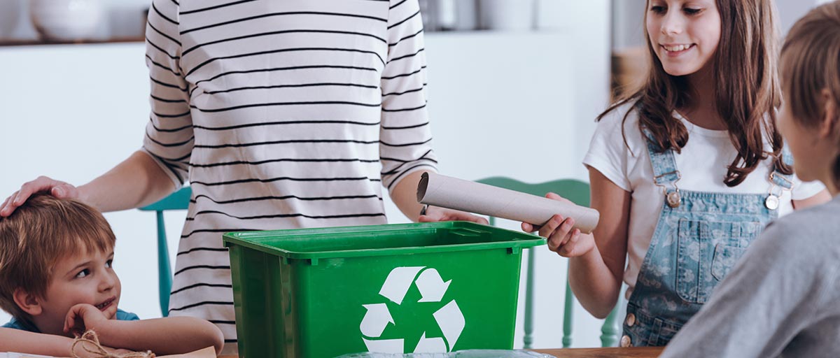 Aikuinen ja lapset lajittelevat kotitalouden jätteitä