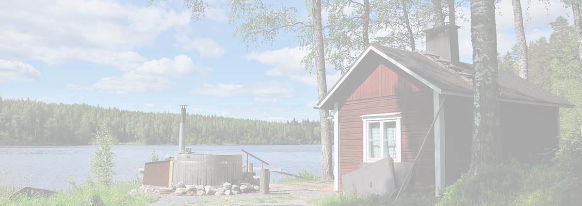 Punainen mökki ja paljun järven rannalla.