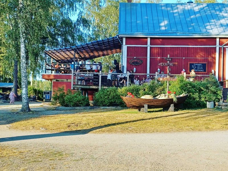 Leirintäalue ja ravintola. Kyltissä reitit saunalle, campingiin ja vessoihin.